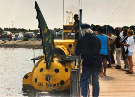 A group of people standing next to a yellow bug

Description automatically generated